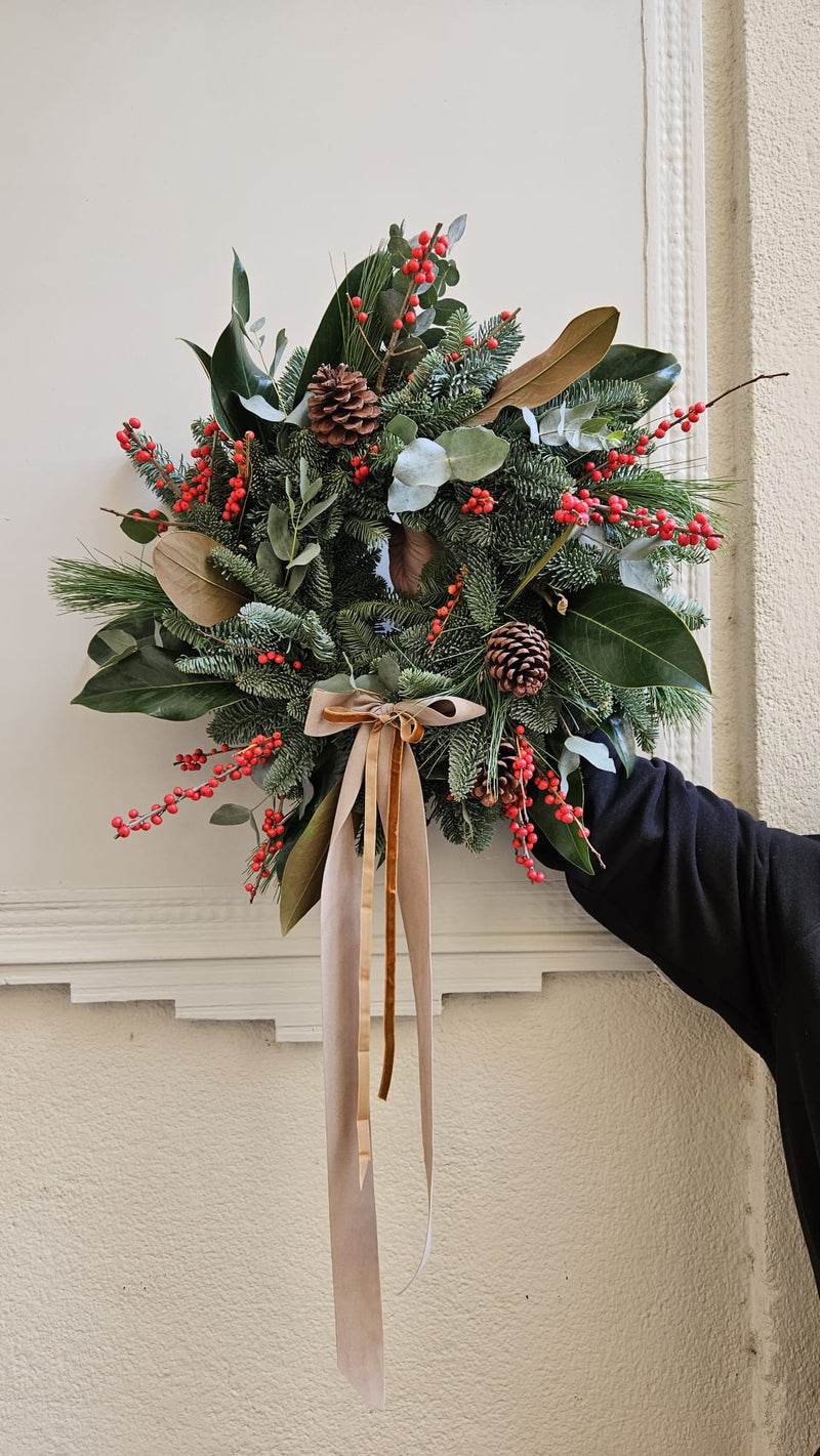 Corona de magnolio, piñas y frutos rojos